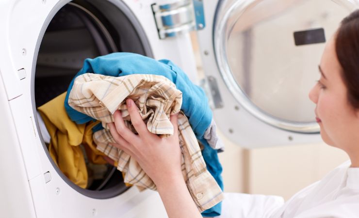 donna mette abiti vestiti in asciugatrice